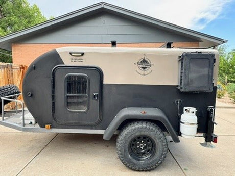 Passenger-side view of the XT50 off-road trailer with entry door, screened window and propane tank