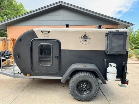Passenger-side view of the XT50 off-road trailer with entry door, screened window and propane tank — photo 2