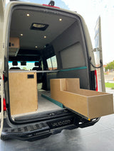 Spacious RV rental interior: a converted camper van with custom wood cabinetry & pull-out storage drawer.