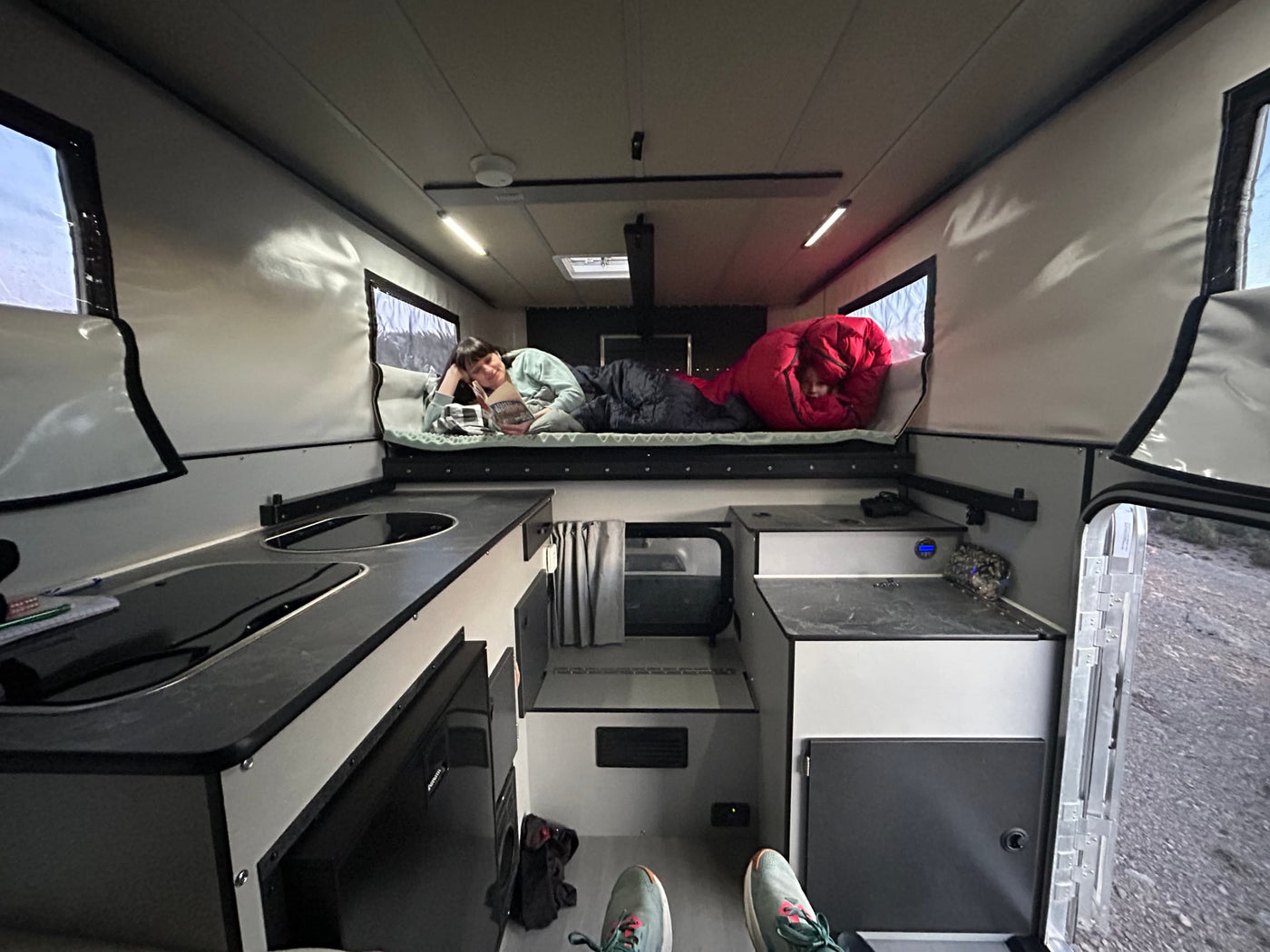 and bright natural light from large windows.|Inside a spacious RV rental: cozy bunk beds with two people relaxing — photo 9