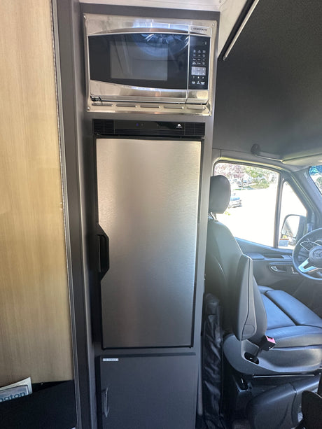Inside this rv rental: A modern kitchenette featuring a Contoure microwave and Norcold refrigerator, perfect for travel convenience.