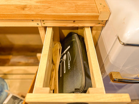 RV rental kitchen drawer open, revealing cooking utensils and a culinary kit. Perfect for camping convenience.