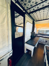 This rv rental features a pop-up camper interior with a starry ceiling, built-in benches, and sleeping area.