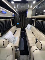 Experience comfort in this luxurious RV rental interior, showcasing plush, quilted seating, ambient lights, and dark flooring.