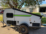 Modern grey pop-up camper, perfect for RV rental. Parked in a residential setting, it features a bright green accent stripe.