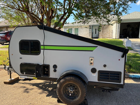 Modern grey pop-up camper, perfect for RV rental. Parked in a residential setting, it features a bright green accent stripe.