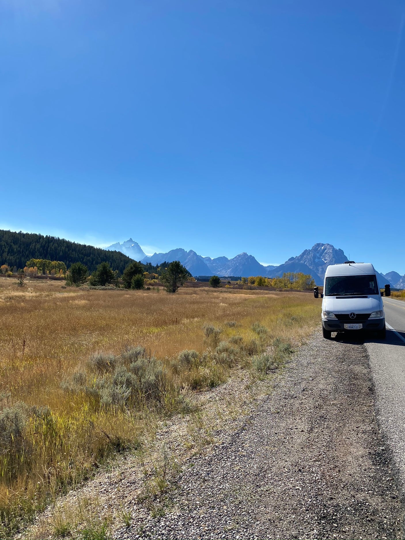 White Sprinter RV rental enjoying a mountain view across golden fields. Perfect road trip!