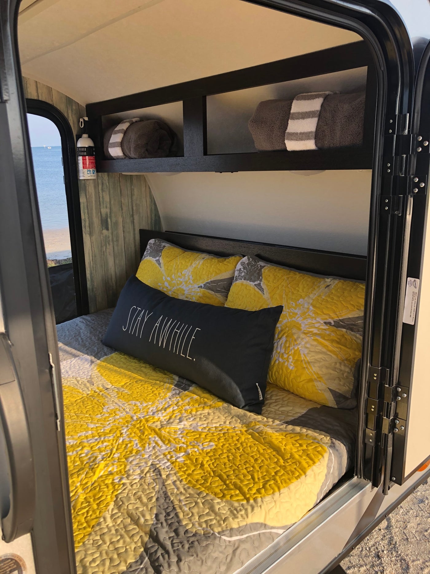 Cozy RV rental interior with yellow bedding and ocean view, featuring a comfortable bed for a relaxing stay. — photo 9