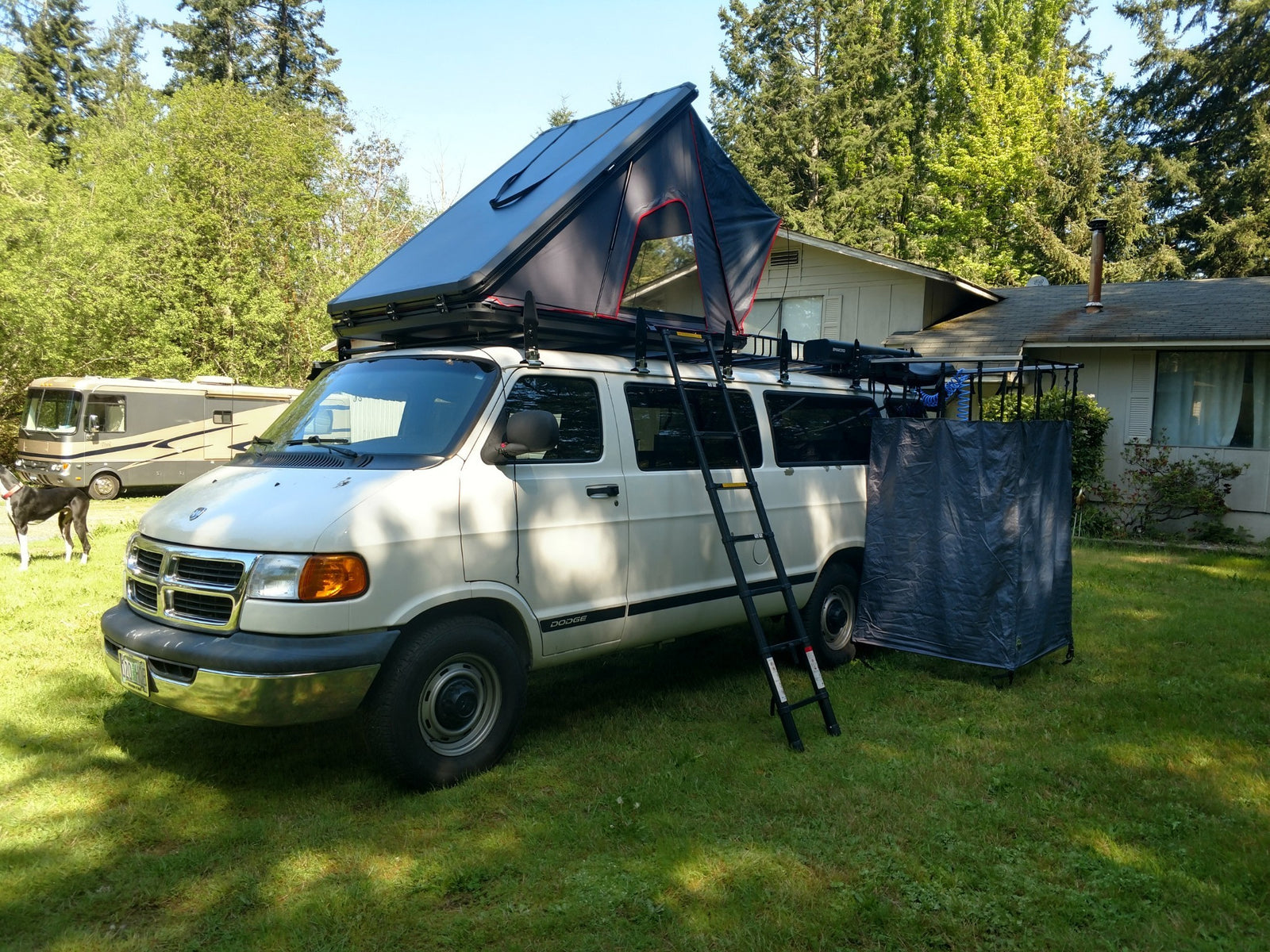 Experience van life! This white Dodge van features a rooftop tent, ladder, and privacy tent for convenient RV rental camping.