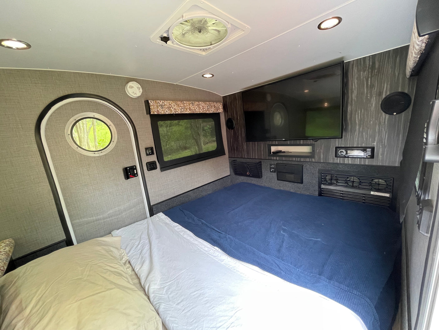 RV rental: Compact, comfortable interior with a bed, TV, and essentials for your next adventure.