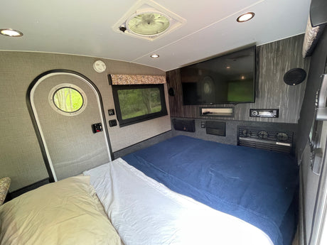RV rental: Compact, comfortable interior with a bed, TV, and essentials for your next adventure.