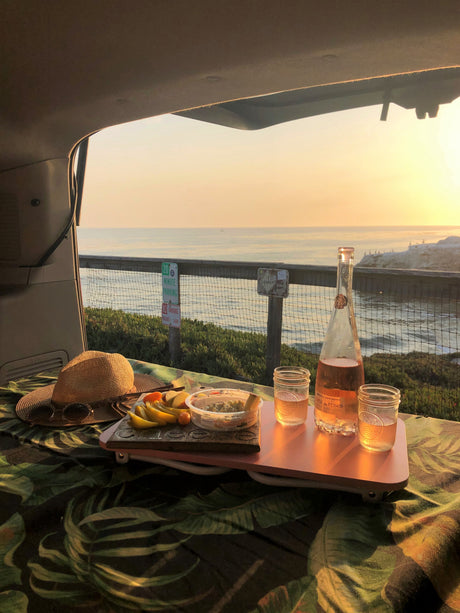 Enjoy a beautiful sunset picnic from your RV rental, with rosé wine, fruit, and dip, overlooking the ocean.