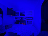 Cozy blue-lit RV rental interior with bed, TV, AC, and electric fireplace. Enjoy relaxing amenities in this compact space.