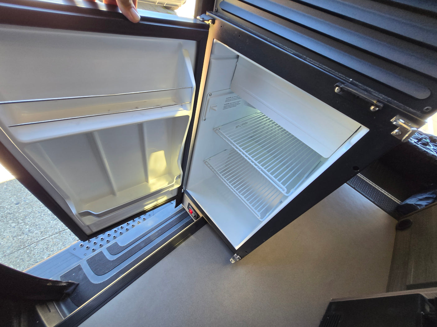 Inside an RV rental, this clean, open refrigerator with wire shelves is ready for your travel adventures.