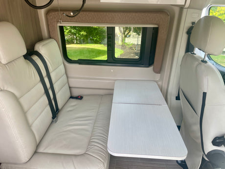 Inside an RV rental: comfy passenger and bench seats, a practical fold-out table, and a clear window for views.