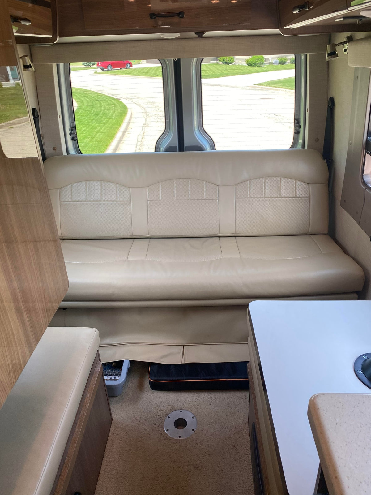 Comfortable RV rental interior with light-colored lounge seating, wood accents, and bright rear windows, ready for road trips. — photo 4