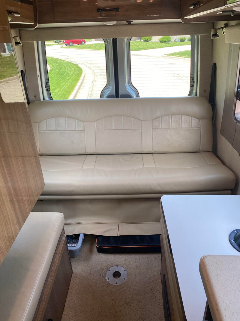 Comfortable RV rental interior with light-colored lounge seating, wood accents, and bright rear windows, ready for road trips. — photo 4