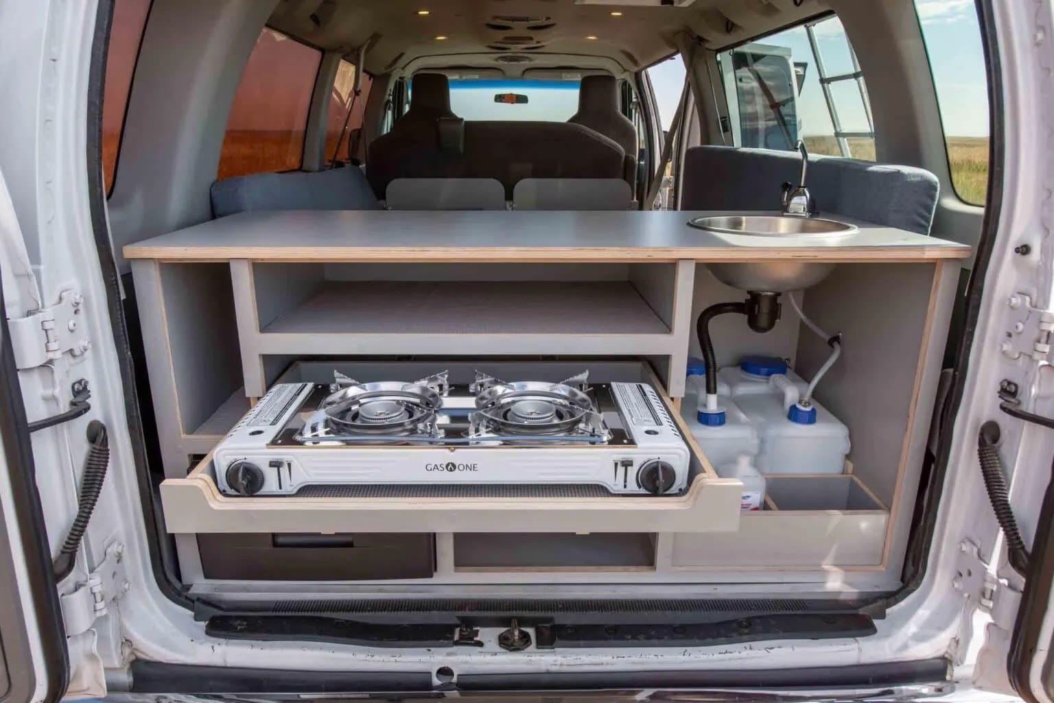 Compact camper van kitchen with pull-out stove and sink, perfect for an rv rental.