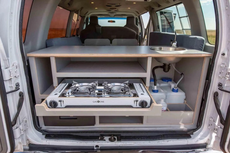  golden field. Perfect for road trips!|This RV rental shows a camper van's rear: integrated kitchen with pull-out stove — photo 7
