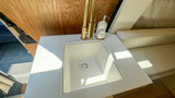 Explore in comfort with this RV rental's sleek interior, featuring a modern sink, gold faucet, and comfortable seating.