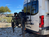 RV rental ready for adventure! White Winnebago van with two bikes on rear rack, sunny desert mountains.