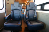 Two black leather captain's chairs with seatbelts offer comfortable passenger seating in this RV rental van interior.