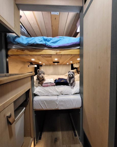 Inside an rv rental: a cozy bunk bed setup with soft lighting and stuffed animal companions on the lower bed.