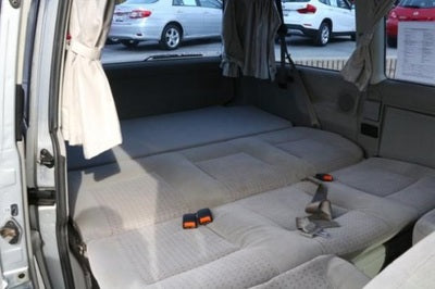RV rental interior showing rear seats folded flat into a sleeping area, with visible seatbelts.