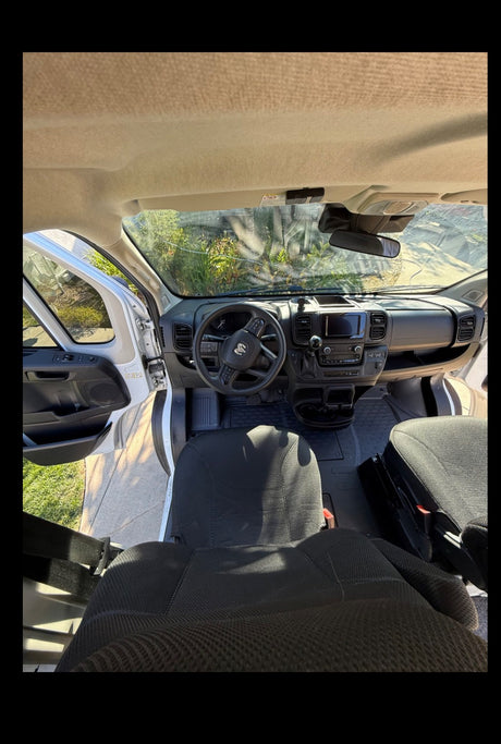RV rental van interior from above: dashboard, steering wheel, and front seats are clearly visible, with an open door.