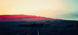 Stunning sunset paints mountains red, seen from a highway. Ideal for an RV rental adventure.