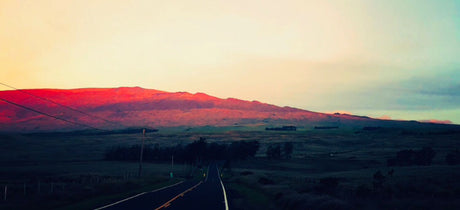 Stunning sunset paints mountains red, seen from a highway. Ideal for an RV rental adventure.