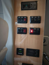 This RV rental features a multi-function control panel, managing power, lighting, water, and tank levels. The battery disconnect light is on.