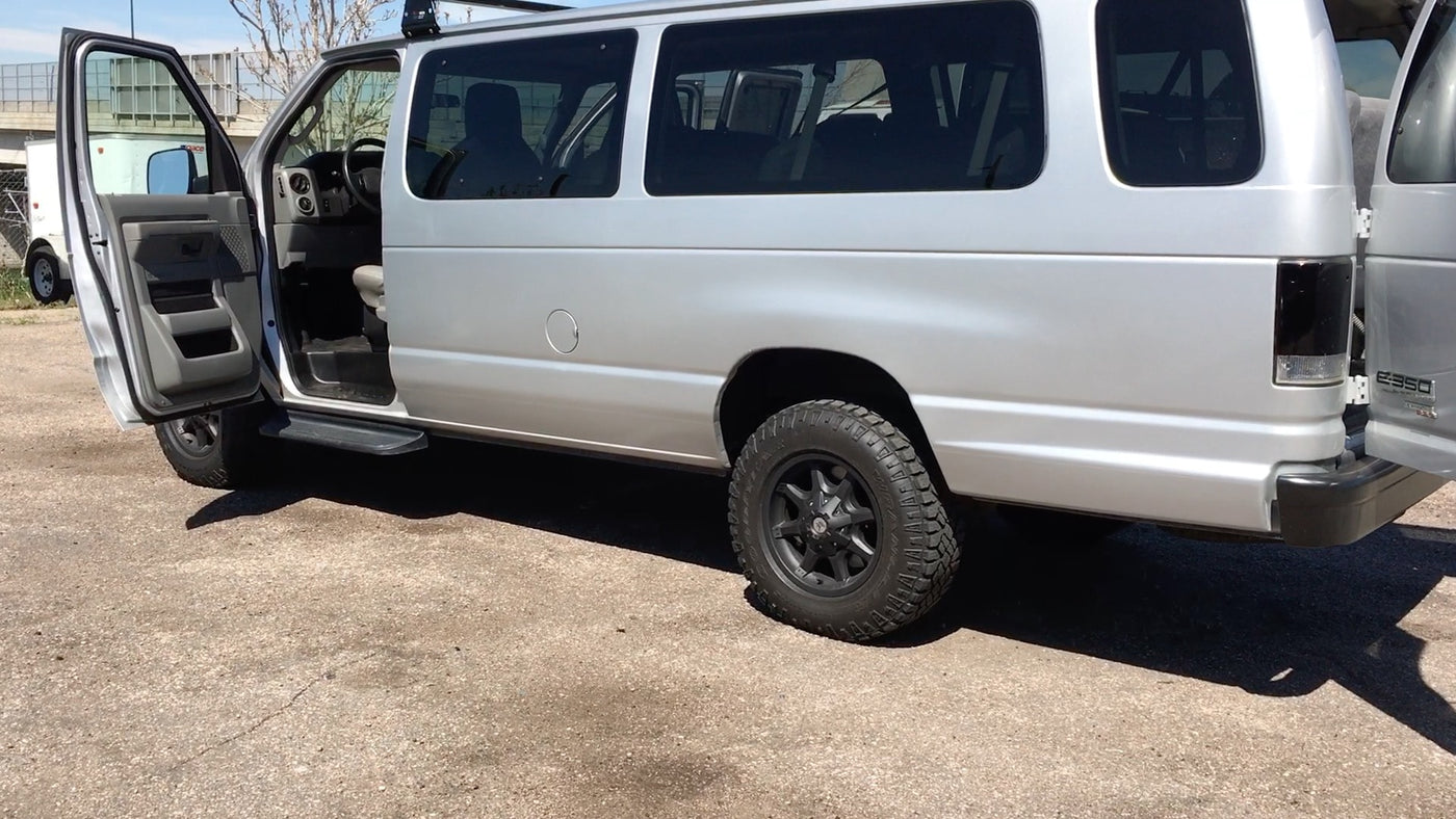  showing spacious interior and roof rack for adventure.|Spacious silver Ford E-350 van with open doors — photo 2