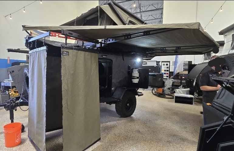 Side view of the XPedition Voyager Sky XE with the Outpost shower enclosure and 270 awning both deployed, rooftop tent open — photo 18