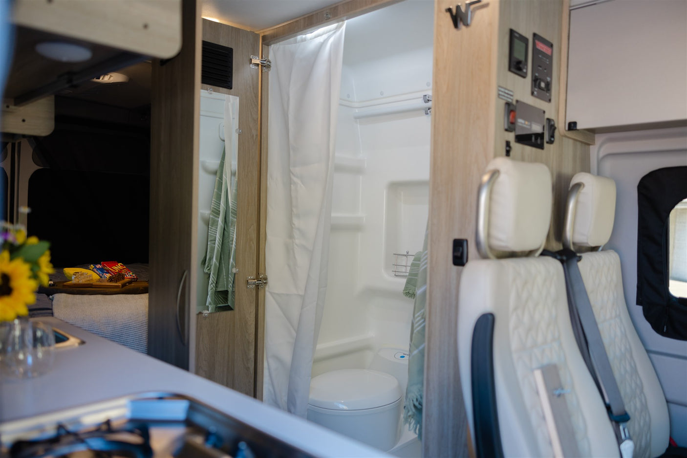 Spacious RV rental interior from front to back, showing kitchen, full bathroom, comfortable bed, and driver's area.