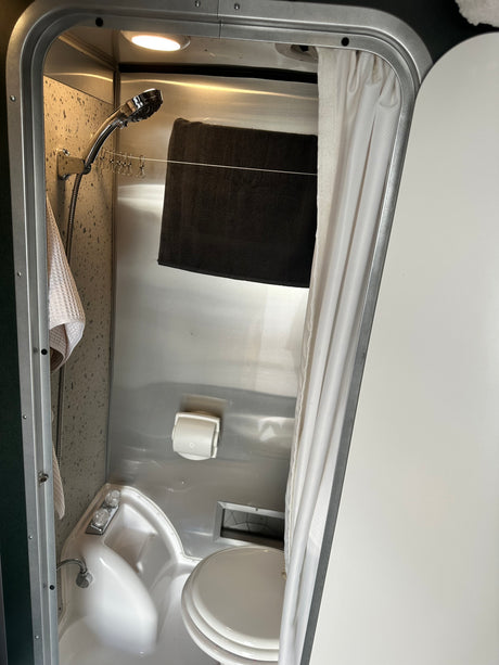 This efficient rv rental wet bath features a shower, toilet, sink, and a handy clothesline for drying, optimized for compact travel.