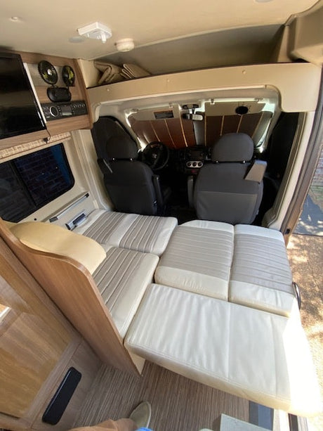 RV rental interior: spacious camper van with convertible bed and forward cockpit view. Ready for your adventure.