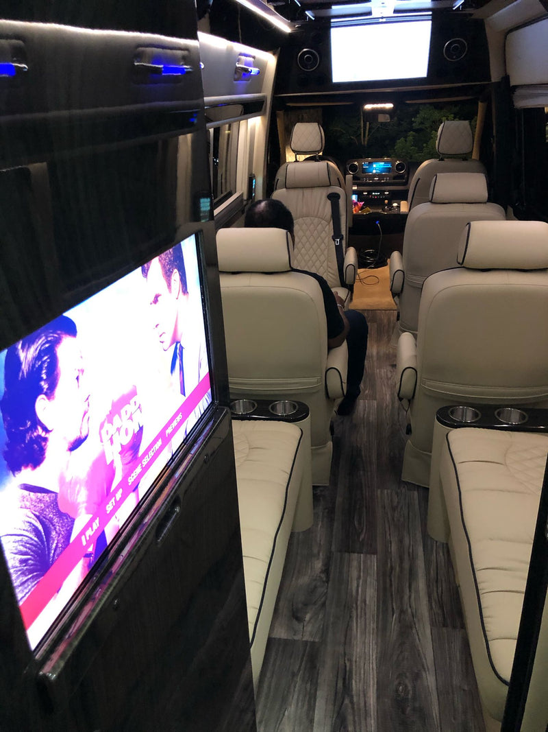 Upscale rv rental interior with cream captain's chairs, wood-look floor, and a large TV showing a film. — photo 14