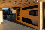 Modern RV rental interior with bamboo cabinetry, slatted ceiling, and hexagon-patterned floor. Includes pull-out table & appliances.