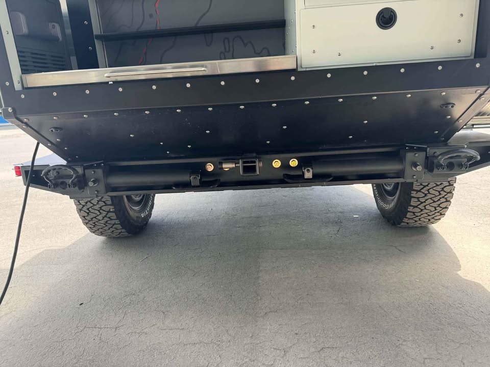 Rear underside of the XPedition Voyager Sky XE showing the receiver crossmember, stabilizer jack mounts, wiring connections and BFGoodrich off-road tires — photo 14