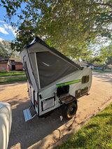 Pop-up RV rental set up for outdoor cooking, with an attached grill for camping.