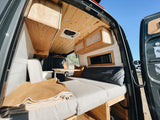 Cozy RV rental interior with wooden ceiling, cabinets, and a comfortable bed. Perfect for your road trip adventures.