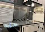 Explore this RV rental's kitchen, showcasing a modern counter, sink with faucet, and smart storage solutions.