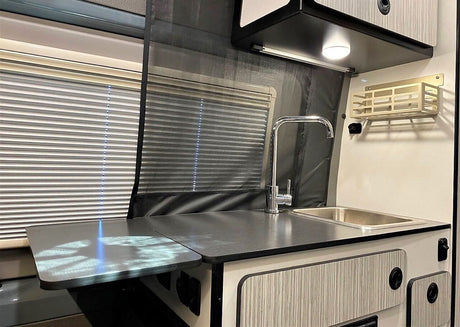 Explore this RV rental's kitchen, showcasing a modern counter, sink with faucet, and smart storage solutions.