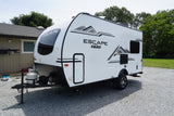A white Escape travel trailer (RV) by KZ, parked on gravel. A versatile choice for your next rv rental.