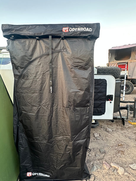 Black OPENROAD privacy enclosure extending from an rv rental trailer, perfect for outdoor showering or changing while camping.