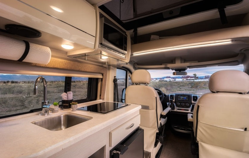  and scenic window view for comfortable mobile living.|Explore this bright rv rental interior! Compact kitchen with sink/stove