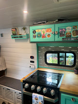 RV rental: Bright, personalized camper van kitchen with teal cabinets, wood counters, and built-in bench seating.