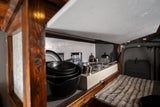 Inside a well-equipped RV rental: a compact kitchen with cookware & a comfortable bed. Ideal for road trips.