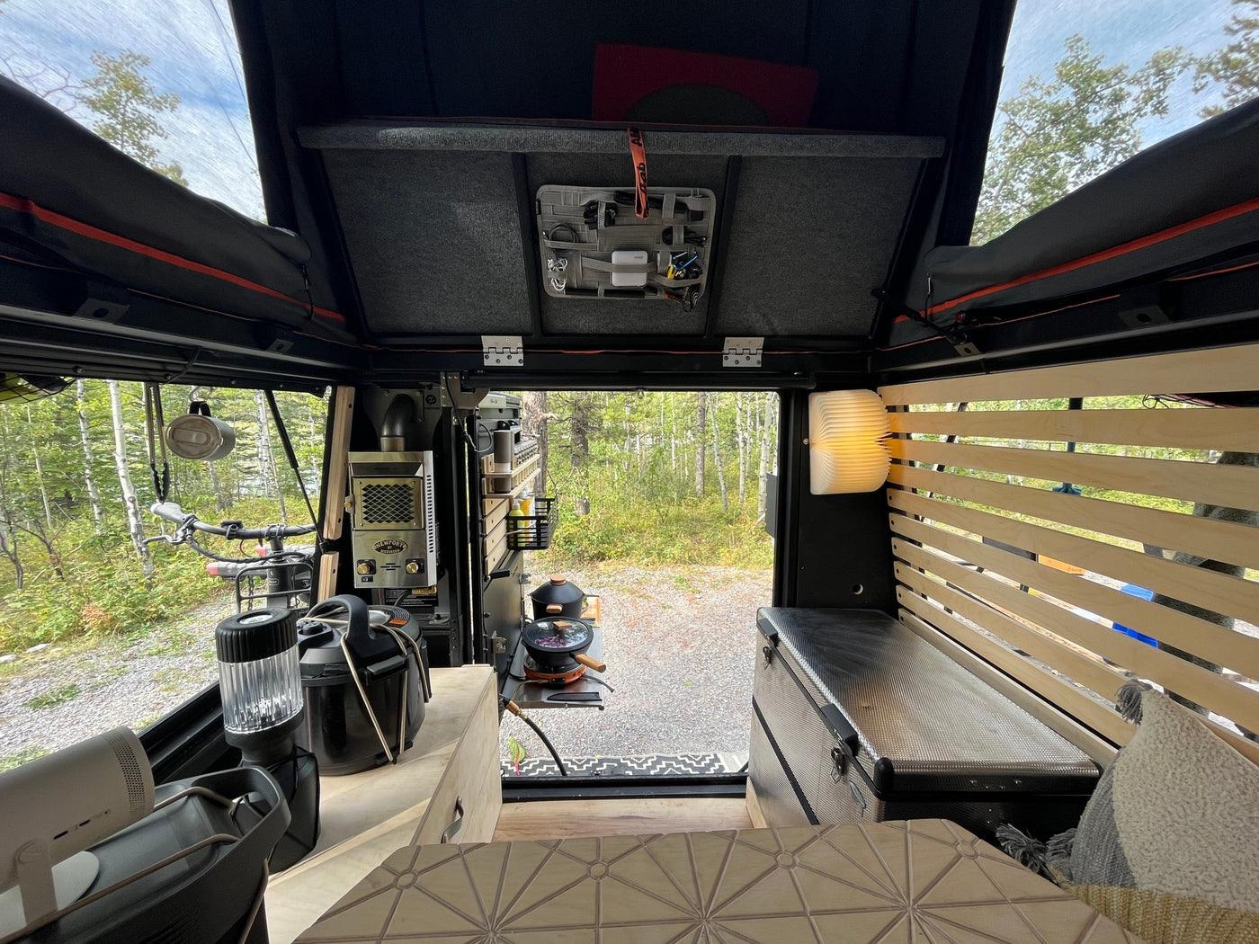 RV rental interior: comfy bed with slatted frame, compact kitchen, bike storage, and nature views. Your adventure awaits! — photo 17